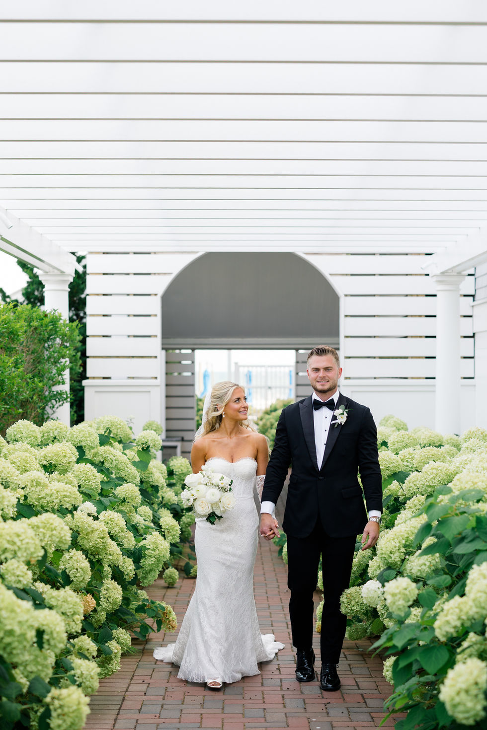 bride and groom on walkway surrounded by lime green hydrangeas at Wychmere Beach Resort