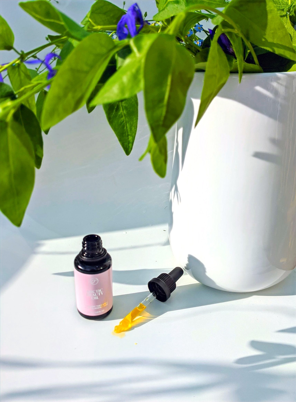 Koti Lifestyle | Flow Cosmetics Arctic Beauty Oil and a white vase full of leaves and blue flowers, applying technique for facial oil