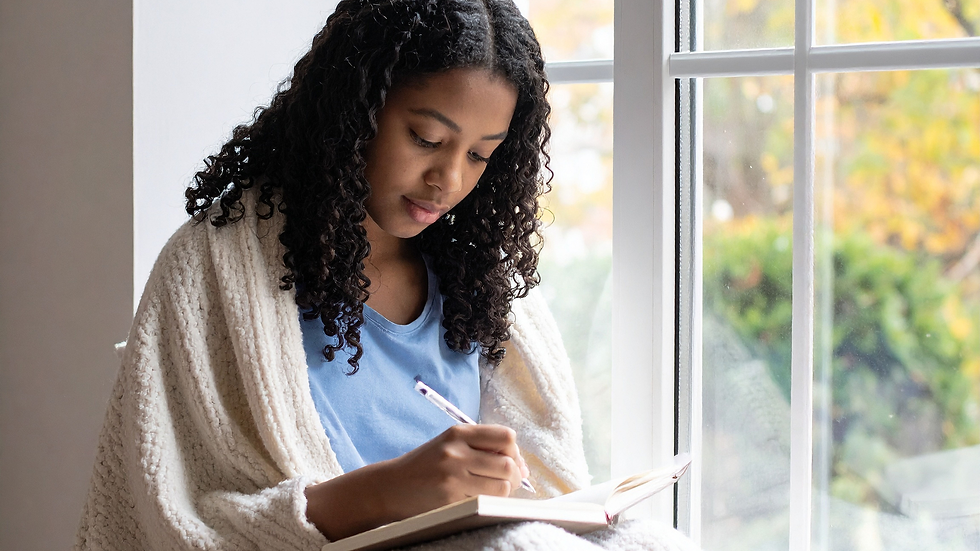 Woman writing in a journal in a sunny peaceful space, reflecting on holistic wellness, mindfulness, and Ayurvedic self-care practices for body, mind, and spirit balance
