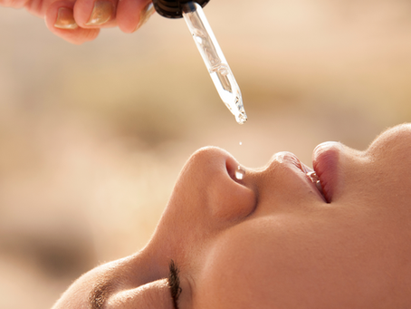 Close-up of a dropper applying nasya nose oil to a person's nostrils with a soft, blurred background. The mood is serene and calming.