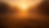 Golden sunrise over a misty grass field, with dark trees framing the horizon and warm orange light creating a calm mood.