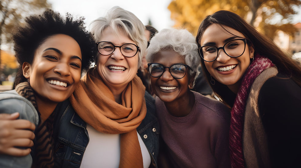 Four diverse women smiling warmly, wearing glasses and scarves, in an autumn park setting with yellow leaves, exuding joy and friendship.