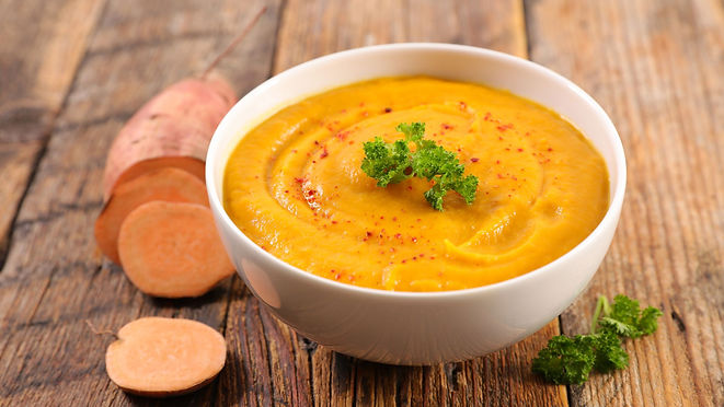 Ayurvedic Turmeric Sweet Potato Cauliflower Soup | For Vata, Pitta, and Kapha image Ayurveda sweet potato soup in a white bowl on a wood counter