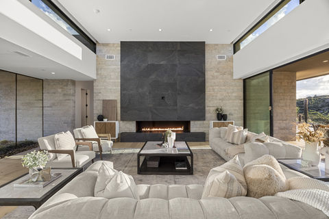 Luxury living room with fireplace, sofas and windows showcasing modern design.