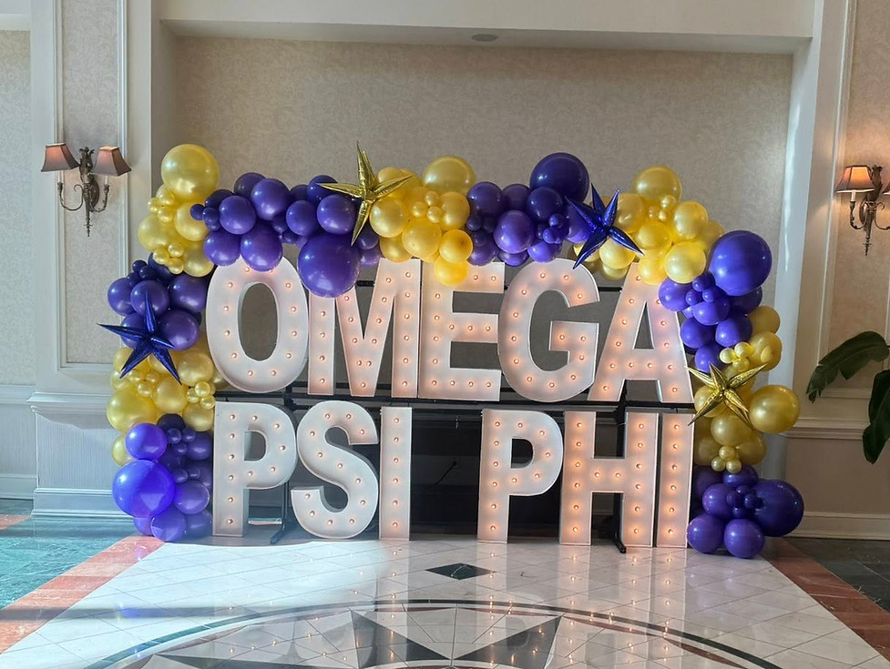 Omega Psi Phi marquee letters with purple and gold balloons