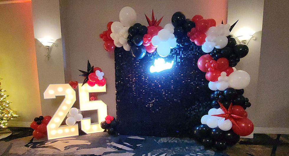 Red, white, and black balloon arch over a backdrop for rentals.