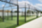 Modern outdoor padel courts with panoramic glass walls at Padel Club Palm Beach under a clear blue sky.