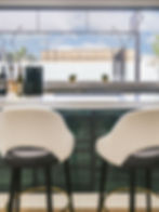 Elegant bar at Padel Club Palm Beach with wine selection, modern seating, and court views.
