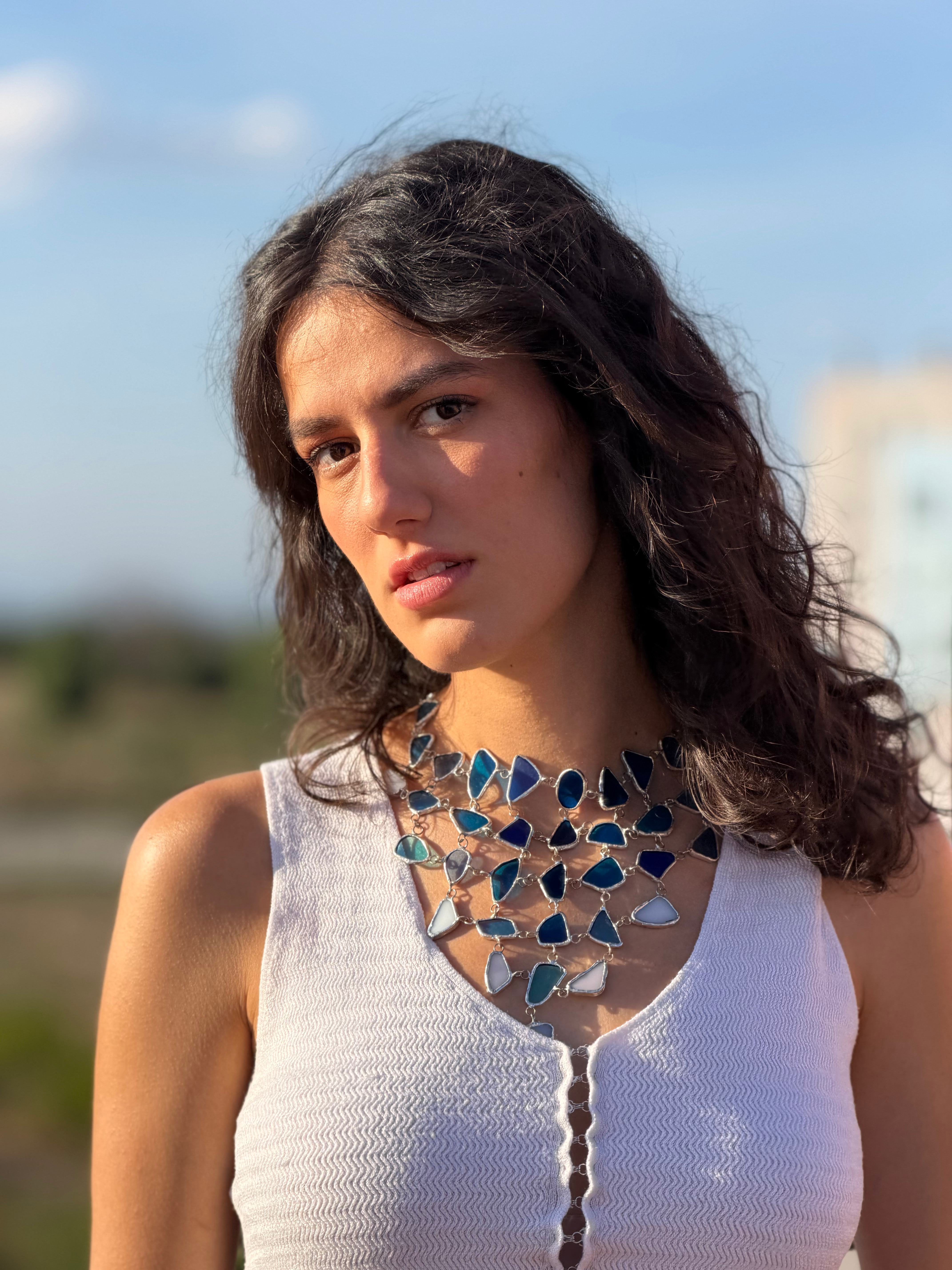 Plano de cerca chica con collar bonito puesto de piedras de vidrio en diferentes tonos de azul y blanco estilo marino