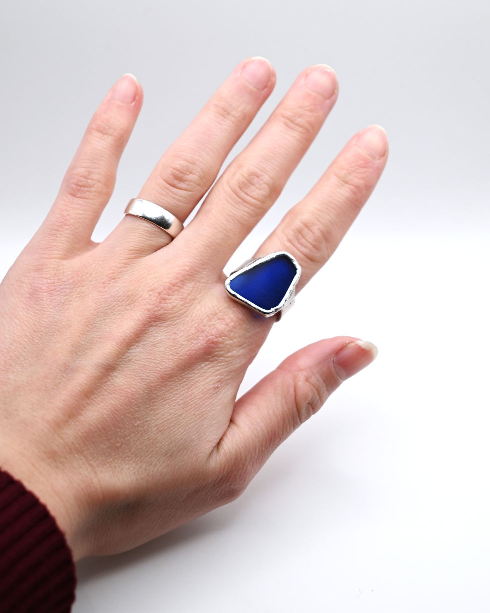 Mano con anillo puesto banda plata con vidrio azul estilo Tiffany