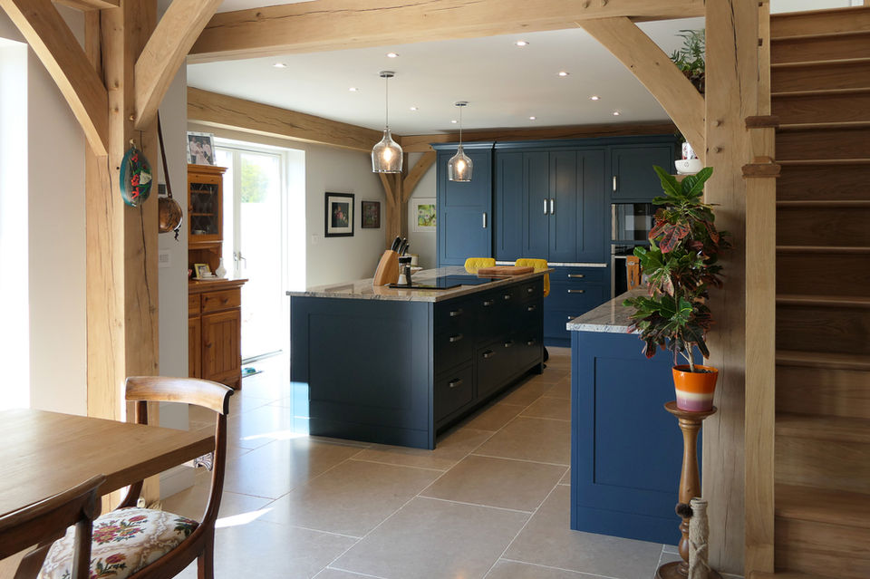 a handcrafted custom shaker kitchen featuring dark blue painted cabinetry, satin nickel handles, a grey granite worktop and warm rustic oak detailing throughout