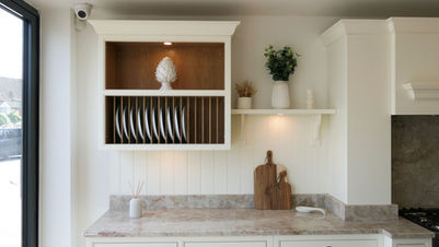 a handmade bespoke shaker kitchen painted in a soft cream colour featuring an oak wall cabinet with an integrated oak plate rack