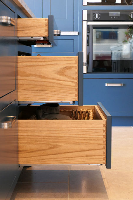 a handcrafted custom shaker kitchen featuring dark blue painted cabinetry, satin nickel handles, a grey granite worktop and warm rustic oak detailing throughout