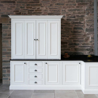 a bespoke handmade shaker kitchen with bright white kitchen cabinetry and a luxurious kitchen island