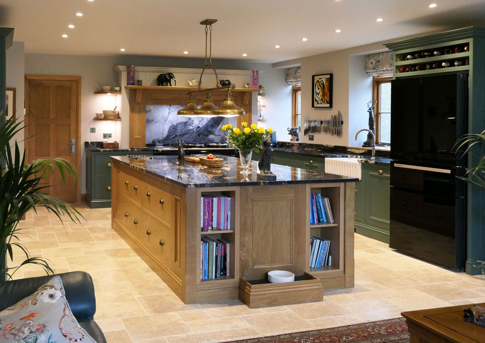 a handcrafted bespoke shaker kitchen with soft green perimeter cabinetry, a stunning oak kitchen island, a beautiful black worktop with gold details, a custom brass worktop and many more bespoke kitchen details