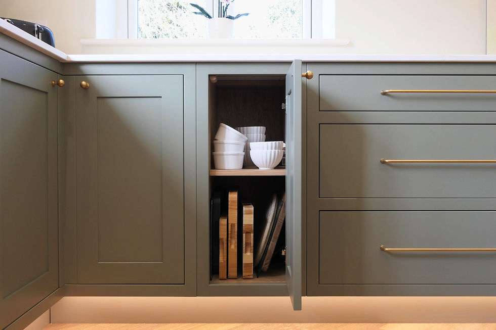 a handcrafted bespoke shaker kitchen painted in a light green colour featuring an open cabinetry door with soft close mechanisms