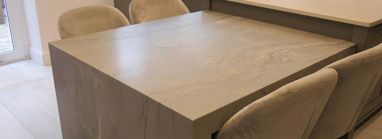 a handcrafted, bespoke shaker kitchen painted in a soft grey colour and satin brass handles. the deign features accents of walnut wooden and bespoke kitchen details