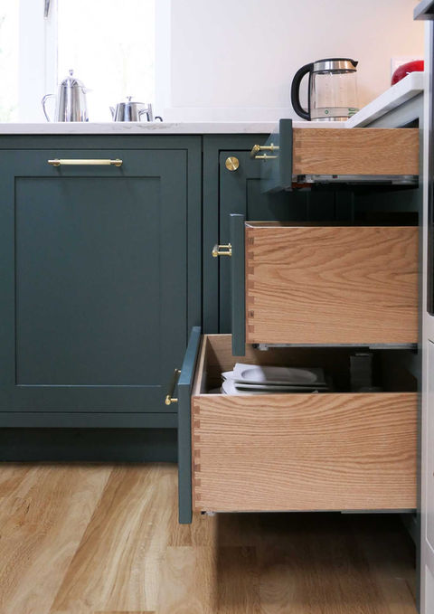 a handcrafted bespoke shaker kitchen with a peninsula design layout, a two-toned colour palette, a custom oak dining table and bespoke kitchen features throughout
