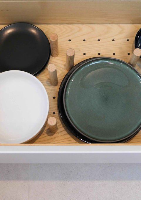 A handmade, modern kitchen with smooth white kitchen cabinetry, a bespoke waterfall worktop, ash wooden features, bespoke detailing and innovative storage solutions