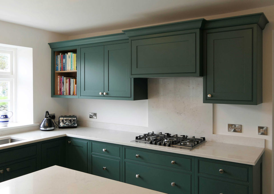 a handcrafted, bespoke shaker kitchen with dark green kitchen cabinetry, a bespoke kitchen dresser, a custom kitchen island, oak storage solutions, integrated appliances, satin nickel handles and bespoke kitchen details