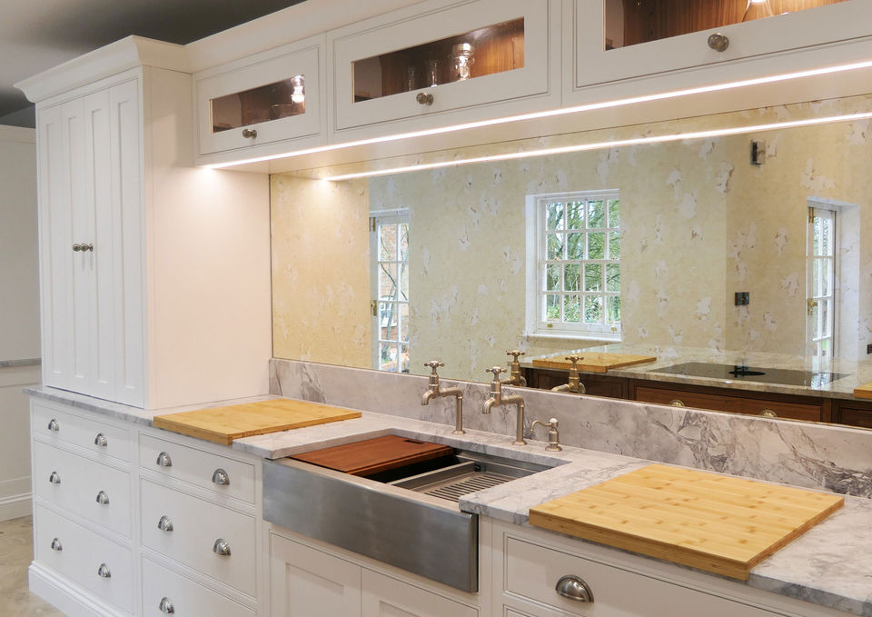 This handmade, bespoke shaker kitchen features beautiful white cabinetry and two luxurious walnut kitchen islands; paired with pewter-coloured handles, this kitchen design is the epitome of luxury. This kitchen features walnut kitchen accessories, integrated appliances, as bespoke walnut pantry and innovative storage features.
