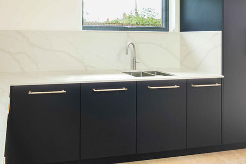 a handmade modern kitchen with dark blue kitchen cabinetry, satin nickel handles, oak wooden details and bespoke kitchen features