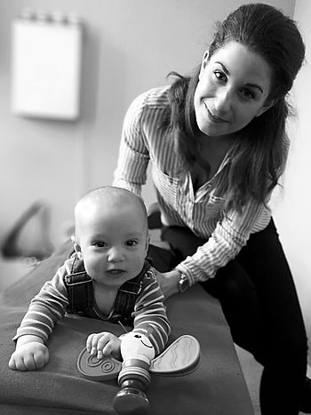 woman treating baby, baby gettin an adjustment, smiling baby on chiropractic table, baby playing with a toy, smiling baby with female chiropactor