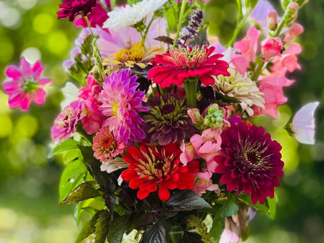 Fresh cut summer bouquet featuring zinnias, cosmos, basil, and assorted farm-grown blooms in bright, cheerful colors.