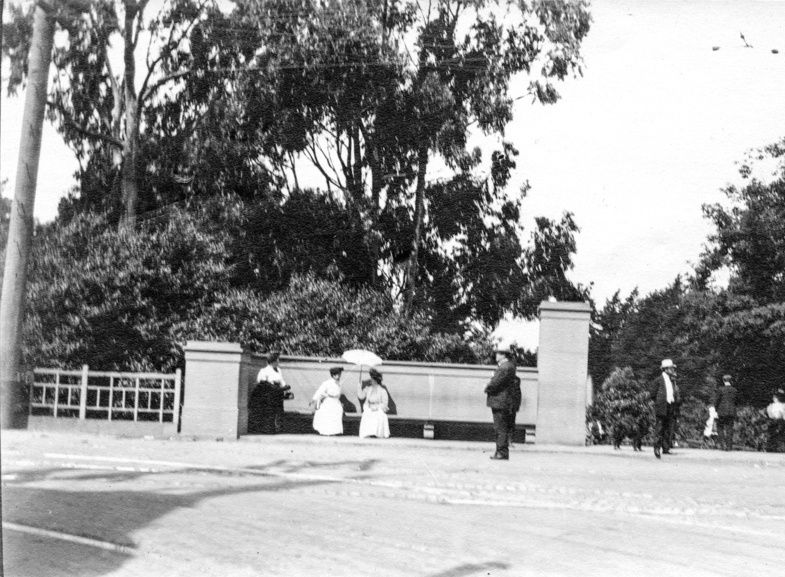 Page title is "History." Image: People gathering at a bench at the intersection of Stanyan at Haight on May 31, 1909. The womens are wearing long skirts and carrying parasols; the men are wearing hats.