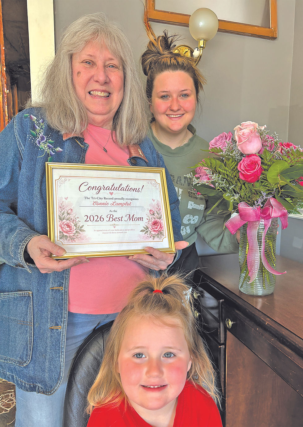 SPECIAL MOTHER… Three generations of love are pictured as Connie Lamplot (center), proudly holds her certificate after being named the Tri-City Record’s 2026 Best Mom. Connie earned the honor through a heartfelt nomination letter written by her granddaughter Autymn Haney (right). Great-granddaughter Aria represents the family’s third generation celebrating the special occasion. (TCR photo by Angela Widdis)