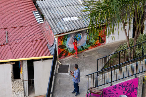 Vue en plongée sur un père et sa fille qui joue devant un graffiti coloré.