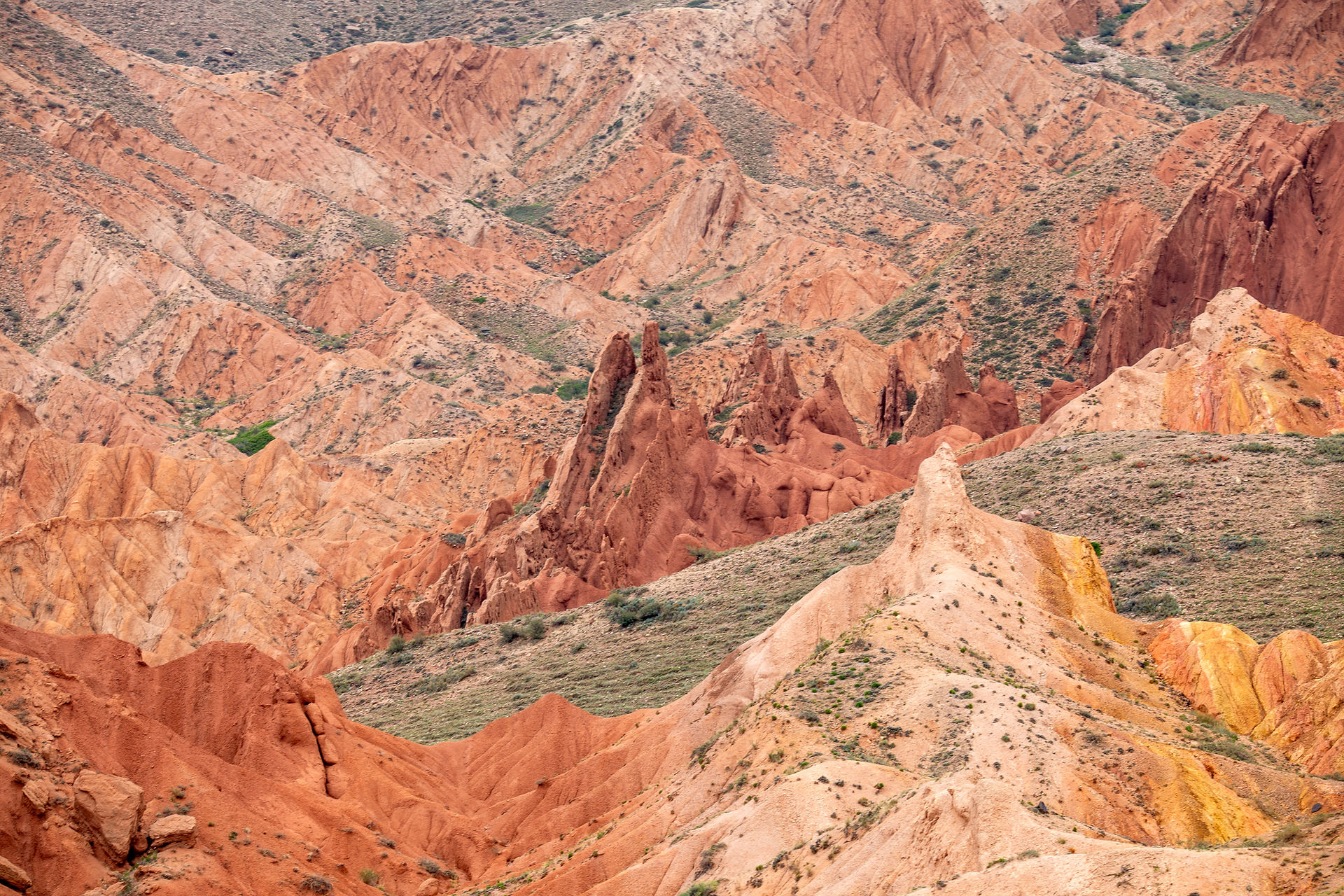 Du jaune, du vert, du rouge, du marron, du orange se dessinent en strates sur les roches en formes de dents du canyon Skazka