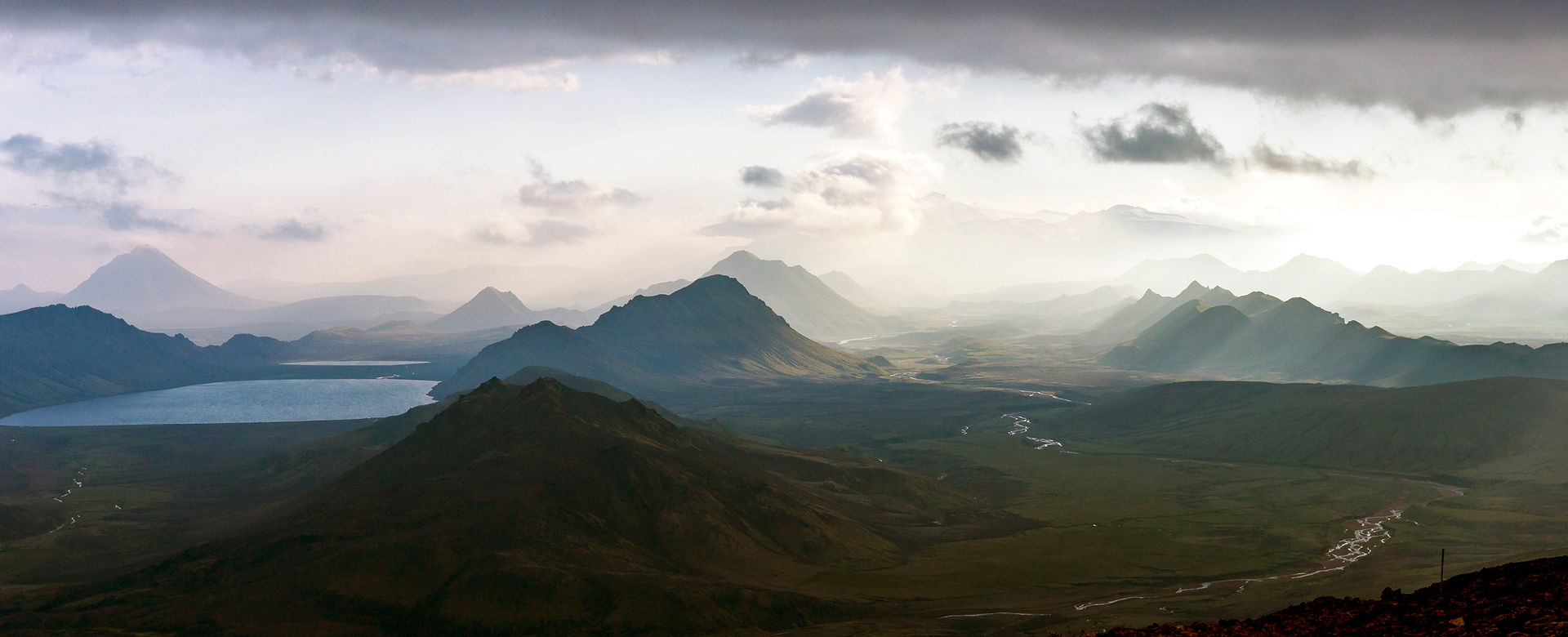Panorama à couper le souffle sur une vallée islandaise pendant le trek Laugavegur, on aperçoit de nombreuses montagnes, une vallée immense et un lac