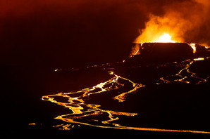 Le gros cratère du volcan Geldingadalur est en éruption et crache vers le ciel de la lave en fusion qui coulent ensuite dans la paysage en rivières lumineuses