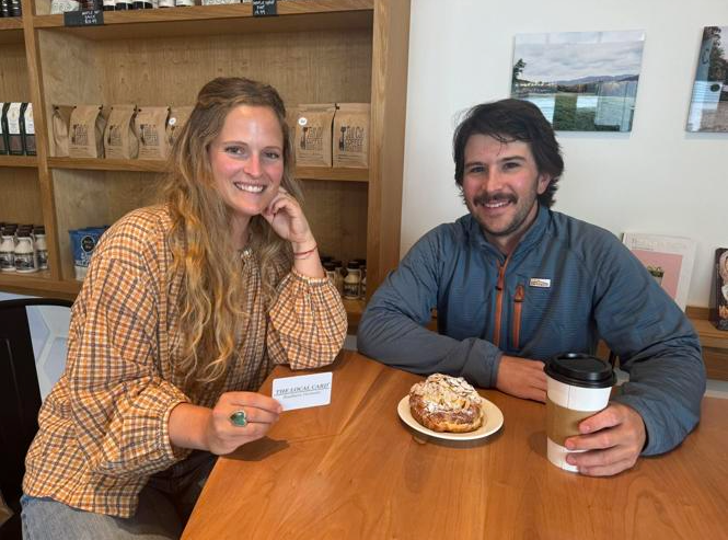 owners of the local card at a table showing off the carb with coffee and pastries