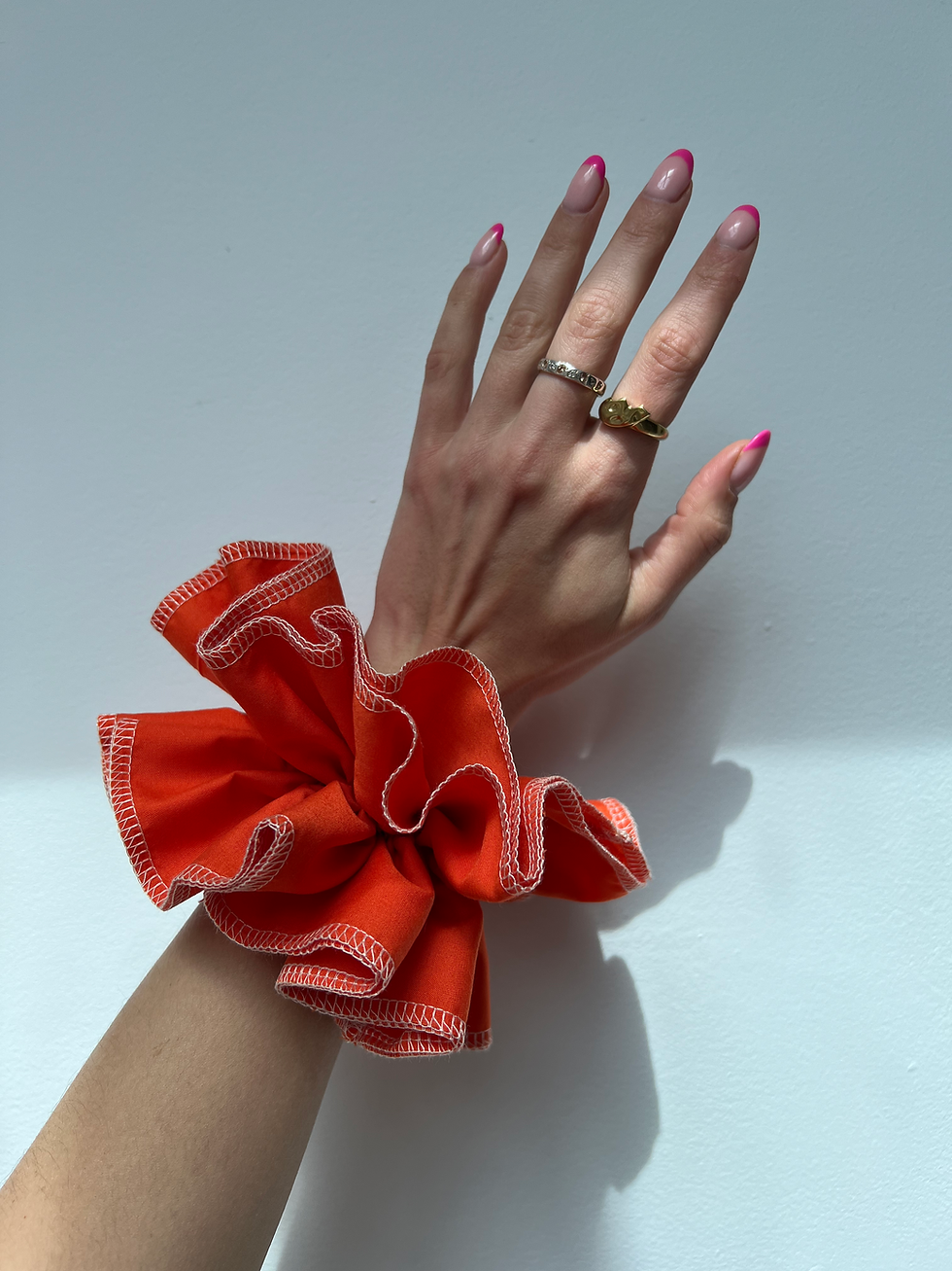 Thumbnail: Hand wearing an orange hair scrunchie