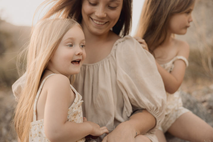 Laughing child leans into mother during outdoor family session—Los Angeles lifestyle family photos with warm light and soft natural textures.