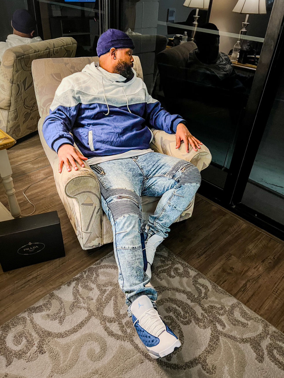 a man sitting in a chair with a prada box in the background