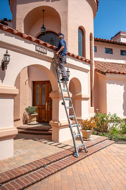 A turn key property inspector on a latter looking at a roof