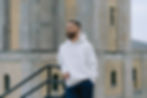 Michael in a white pullover leaning against the stairs.