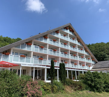 Large hotel building with balconies surrounded by greenery