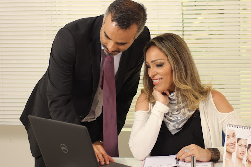 A man and woman in business attire looking at a laptop.