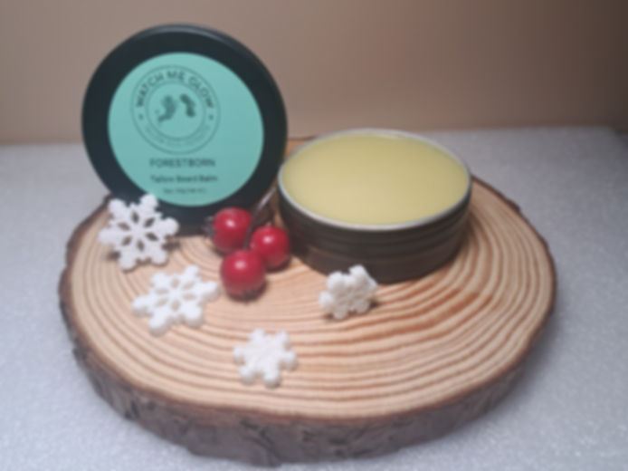 Open black tin with cream on a circular wood cutting with snow flakes and berries