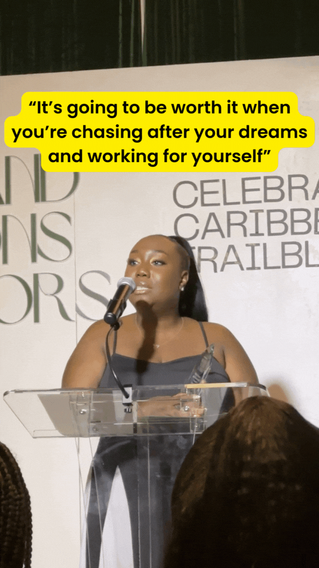 A lady with Black dress speaks passionately about her business behind her a white backdrop with lights