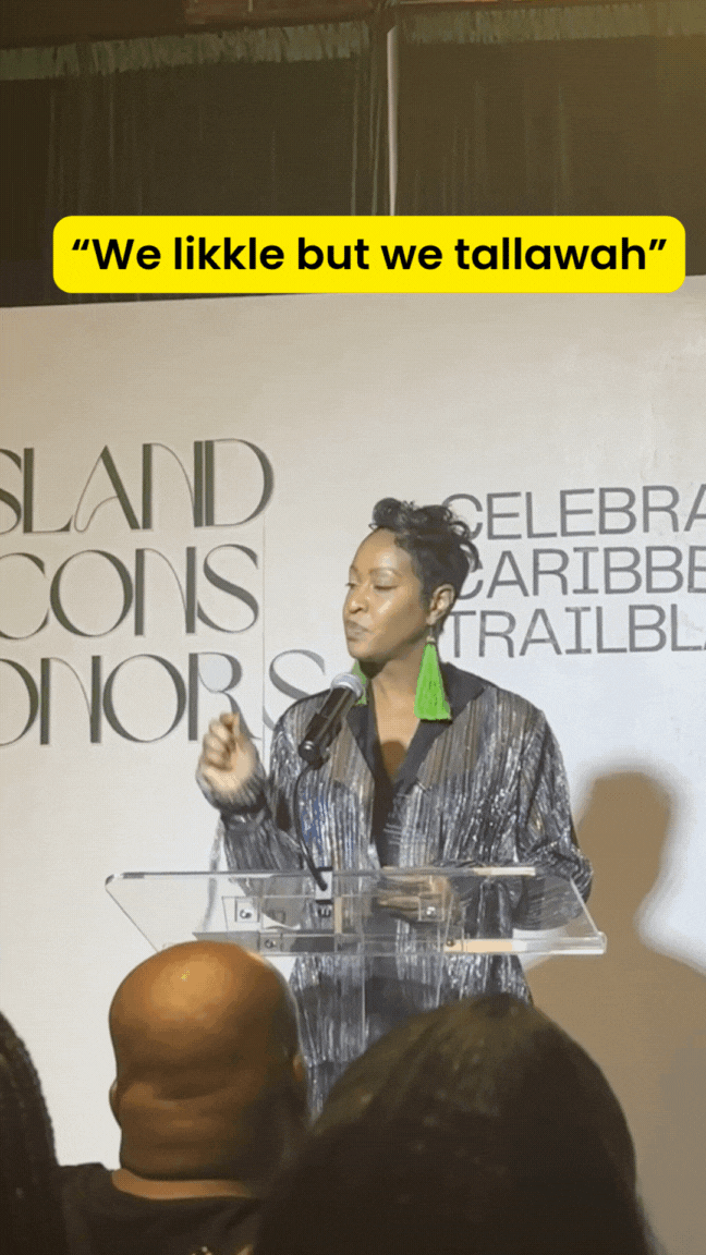 A lady with green earrings speaks passionately about her business behind her a white backdrop with lights
