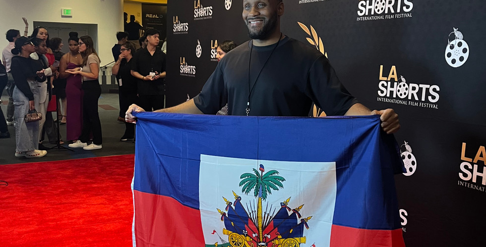 A young man smiling holding a haitian flag at the LA shorts film festival