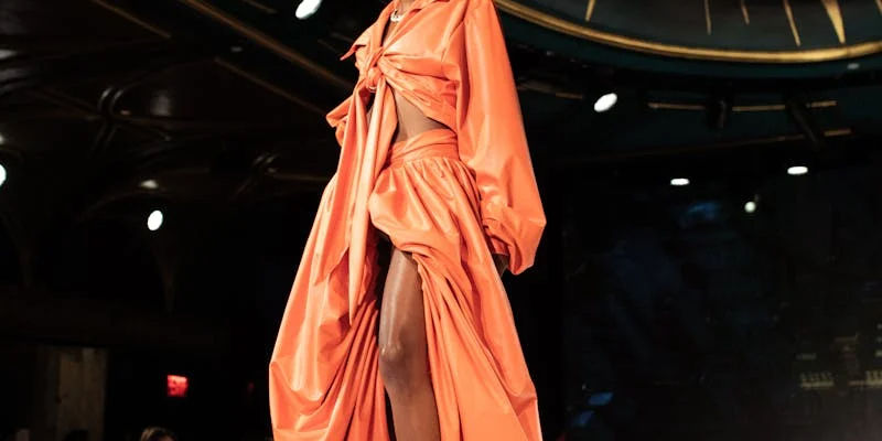 A lady in orange standing infront of bright white light