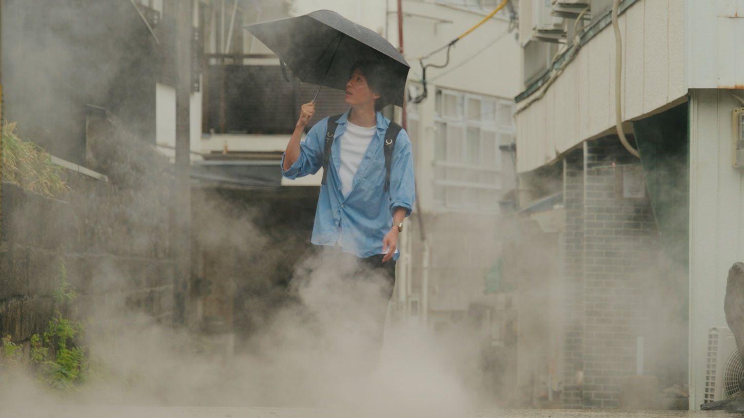 Sho Ikushima walks through Beppu City, Kyushu, Japan with an umbrella on his way to the Beppu Onsen on Sauna Channel.