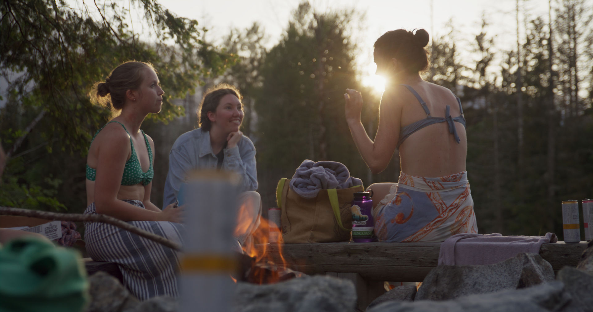 Жінки спілкуються та відпочивають на заході сонця після купання у холодній річці та відвідування сауни в Британській Колумбії.