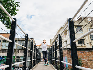 Jo stands outside on a narrow bridge, confidently smiling at the camera